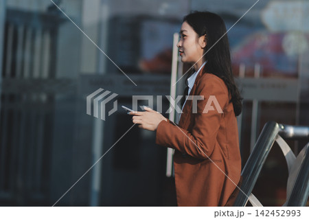 Young businesswoman smiling while working with digital tablet at modern office building Young businesswoman smiling while working with digital tablet at modern office building 142452993