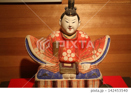 和風の木目を背景にした伝統的な天神様の土人形(郷土玩具) 和風の木目を背景にした伝統的な天神様の土人形(郷土玩具) 142453540