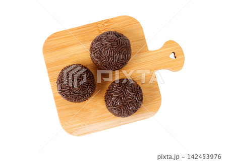 Traditional Brazilian chocolate brigadeiro coated in sprinkles, on a bamboo board, isolated on a white background. Traditional Brazilian chocolate brigadeiro coated in sprinkles, on a bamboo board, isolated on a white background. 142453976