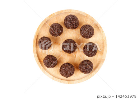 Traditional Brazilian chocolate brigadeiro coated in sprinkles, on a round bamboo tray, isolated on a white background. Traditional Brazilian chocolate brigadeiro coated in sprinkles, on a round bamboo tray, isolated on a white background. 142453979