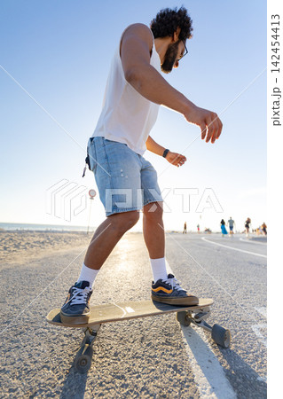 Skateboarding on a sunny beach pathway during the late afternoon Skateboarding on a sunny beach pathway during the late afternoon 142454413