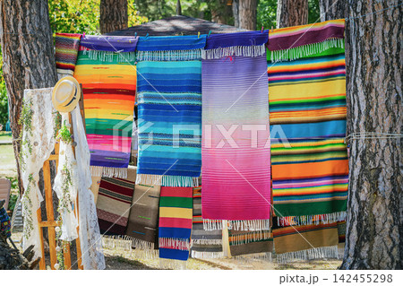 Colorful traditional Bulgarian woven rugs with striped patterns and fringes displayed outdoors in Kotel. Handmade textiles represent local craftsmanship, folk culture and decorative heritage 142455298