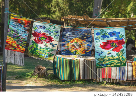 Colorful handmade carpets and woven rugs with floral and artistic patterns displayed outdoors at a traditional craft festival in Kotel, Bulgaria. Bulgarian textile heritage and folk craftsmanship Colorful handmade carpets and woven rugs with floral and artistic patterns displayed outdoors at a traditional craft festival in Kotel, Bulgaria. Bulgarian textile heritage and folk craftsmanship 142455299