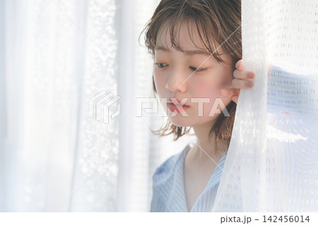カーテンの隙間から覗く女性 カーテンの隙間から覗く女性 142456014