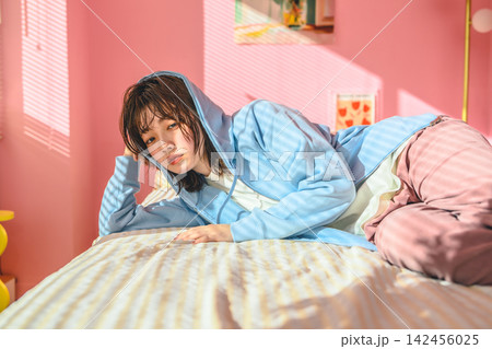 部屋でくつろぐ若い女性、リラックスした表情 部屋でくつろぐ若い女性、リラックスした表情 142456025