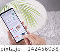 求人サイトで仕事を探す女性の手元写真 (スマホ画面内はオリジナルのサンプル画像) 142456038