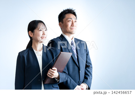 未来を見つめ笑顔を見せるスーツ姿の女性社員と男性社員 142456657