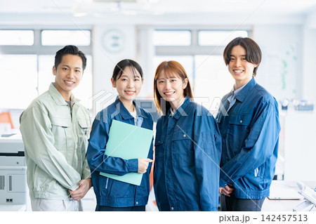 オフィスで笑顔を見せる作業着姿の男女ビジネスパーソン オフィスで笑顔を見せる作業着姿の男女ビジネスパーソン 142457513