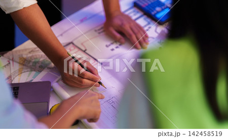 Top angle view of architects hands drafting and reviewing blueprint plans on office desk 142458519