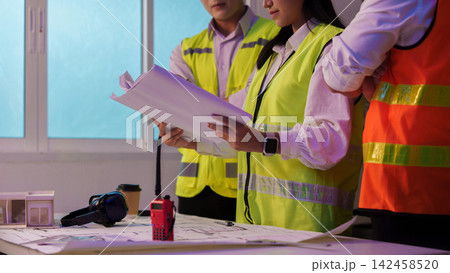 Cropped view of engineers reviewing blueprints at desk for construction project planning Cropped view of engineers reviewing blueprints at desk for construction project planning 142458520