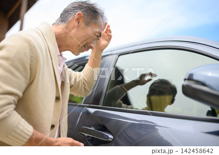 車に近づき窓を見る男性 142458642