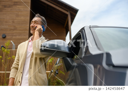 車を背景に電話で話す男性 車を背景に電話で話す男性 142458647