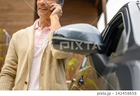 スマホで話す高齢男性、車の横で スマホで話す高齢男性、車の横で 142458658