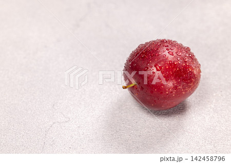 Fresh red plum with water drops on gray background Fresh red plum with water drops on gray background 142458796