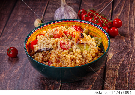 Bulgur salad with roasted vegetables in colorful bowl on rustic wood Bulgur salad with roasted vegetables in colorful bowl on rustic wood 142458894