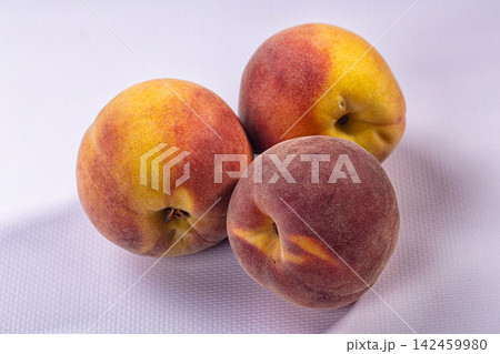 Three ripe peaches on white textured surface with soft lighting and warm color gradient Three ripe peaches on white textured surface with soft lighting and warm color gradient 142459980