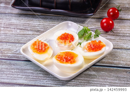 Deviled eggs topped with red caviar on white plate with cherry tomatoes and microgreens Deviled eggs topped with red caviar on white plate with cherry tomatoes and microgreens 142459993