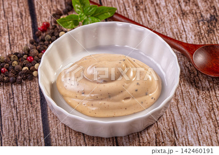 Creamy peppercorn sauce in white bowl with fresh basil and mixed peppercorns on rustic wood Creamy peppercorn sauce in white bowl with fresh basil and mixed peppercorns on rustic wood 142460191