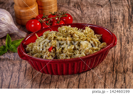 Pesto basmati rice in red bowl with fresh tomatoes, garlic, and basil on rustic wood background Pesto basmati rice in red bowl with fresh tomatoes, garlic, and basil on rustic wood background 142460199