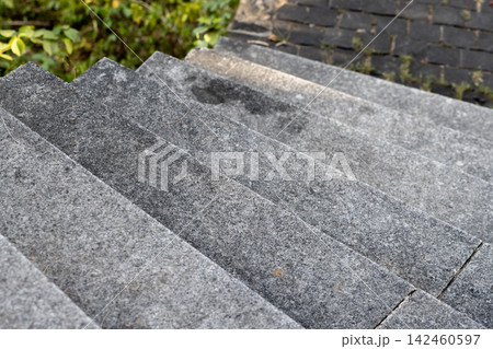 Granite outdoor steps descend toward a paved garden walkway 142460597