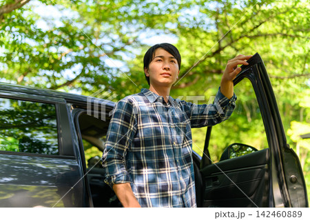 車のドアを開ける男性、夏の木漏れ日の中で 車のドアを開ける男性、夏の木漏れ日の中で 142460889