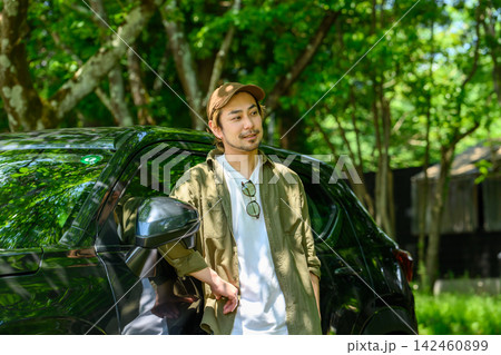 車横でリラックスする男性、夏の緑豊かな森 車横でリラックスする男性、夏の緑豊かな森 142460899