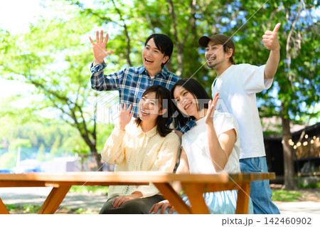 キャンプ場で楽しむ4人の友人、笑顔で手を振る キャンプ場で楽しむ4人の友人、笑顔で手を振る 142460902