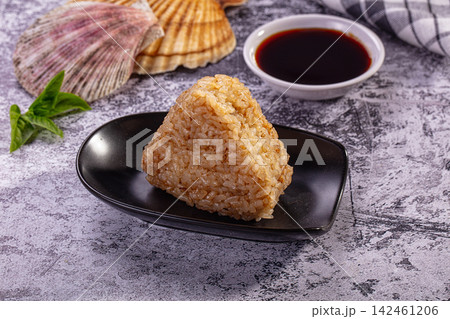Onigiri rice triangle with soy sauce and seashells on textured surface Onigiri rice triangle with soy sauce and seashells on textured surface 142461206