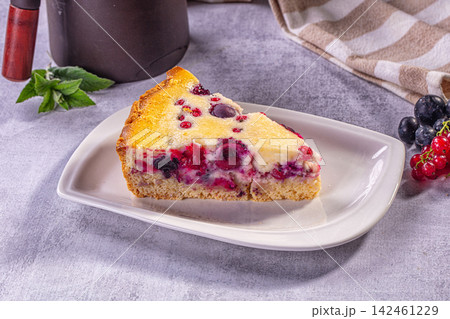 Slice of berry pie with blueberries and red currants on white plate 142461229