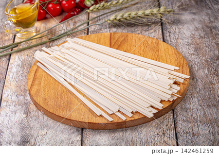 Udon noodles on wooden cutting board with wheat stalks and cherry tomatoes Udon noodles on wooden cutting board with wheat stalks and cherry tomatoes 142461259