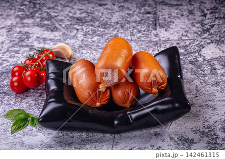 Sausages in black bowl with fresh cherry tomatoes, garlic, and basil on gray background 142461315