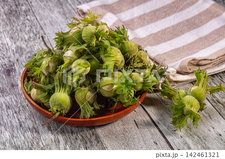 Fresh green hazelnuts or cobnuts in wooden bowl on rustic table Fresh green hazelnuts or cobnuts in wooden bowl on rustic table 142461321