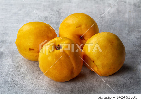 Four yellow nectarines arranged on textured gray surface Four yellow nectarines arranged on textured gray surface 142461335