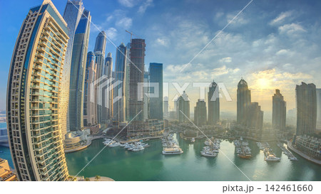 View of modern skyscrapers shining in sunrise lights timelapse in Dubai Marina in Dubai, UAE. View of modern skyscrapers shining in sunrise lights timelapse in Dubai Marina in Dubai, UAE. 142461660