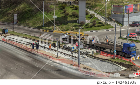 Loader crane for loading and unloading tram rails from truck which stands on a road construction site aerial timelapse 142461938