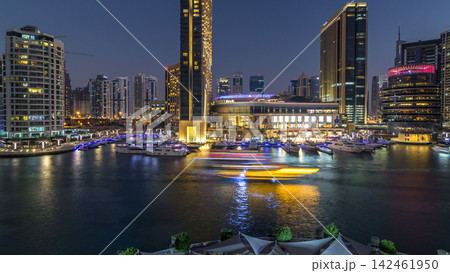 Aerial view of Dubai Marina with shopping mall, restaurants, towers and yachts day to night timelapse, United Arab Emirates. Aerial view of Dubai Marina with shopping mall, restaurants, towers and yachts day to night timelapse, United Arab Emirates. 142461950