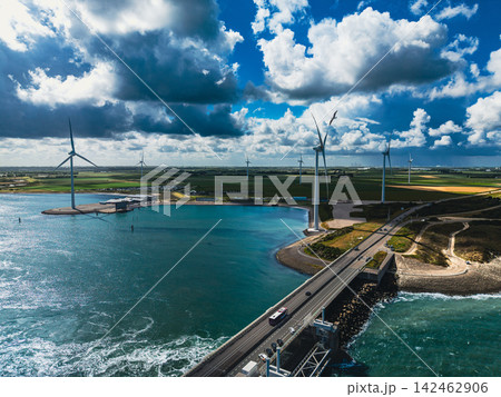 High angle wide horizontal aerial drone photograph of wind turbines, highway, Oosterscheldekering storm barrier, and sea basin in Neeltje Jans, Zeeland, Netherlands on sunny summer day High angle wide horizontal aerial drone photograph of wind turbines, highway, Oosterscheldekering storm barrier, and sea basin in Neeltje Jans, Zeeland, Netherlands on sunny summer day 142462906