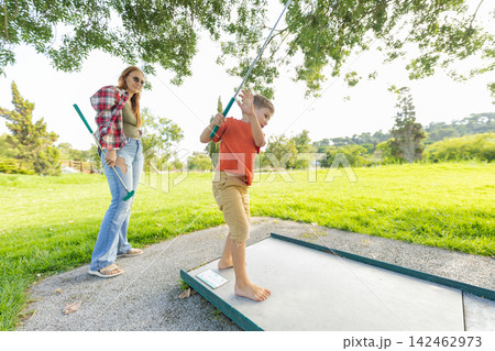 Mother and son playing mini golf together Mother and son playing mini golf together 142462973