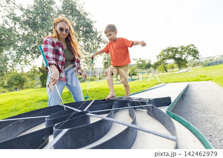 Mother and son playing miniature golf game outdoors Mother and son playing miniature golf game outdoors 142462979