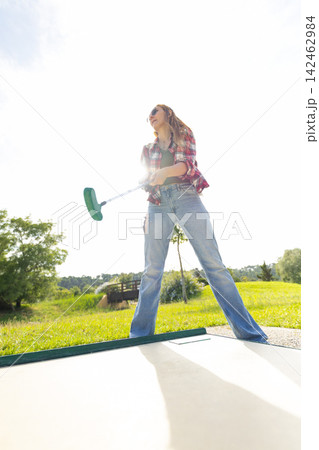 Young woman enjoying mini golf on a sunny day Young woman enjoying mini golf on a sunny day 142462984