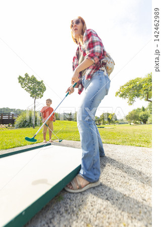 Mother and son playing mini golf outdoors Mother and son playing mini golf outdoors 142462989