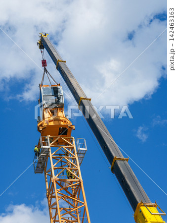 Tower Crane Operator Cab Installation by Mobile Crane with Workers Guiding Assembly High Above Ground Tower Crane Operator Cab Installation by Mobile Crane with Workers Guiding Assembly High Above Ground 142463163