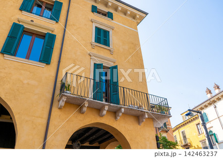 Yellow Italian Building Facade with Green Shutters and Balcony on a Clear Day in Verona, Italy 142463237