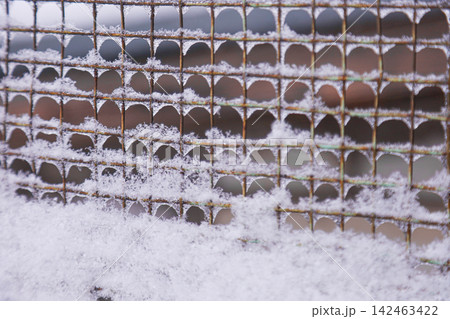 Rusty metal mesh fence covered in fresh white snow Rusty metal mesh fence covered in fresh white snow 142463422