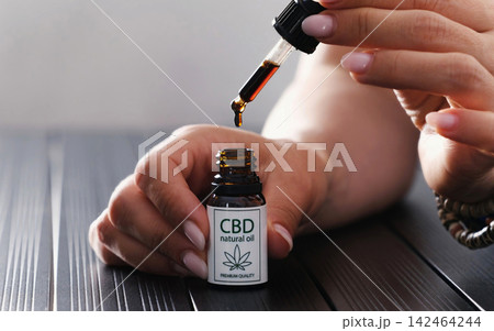 Cbd Oil Dropping From Glass Pipette Into Bottle Cbd Oil Dropping From Glass Pipette Into Bottle 142464244