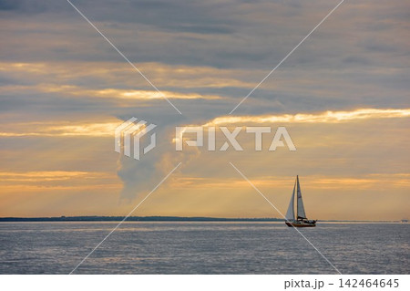 Yachtsmen are sitting amicably on board the boat at incredible sunset, sailing boat is in sailing regatta in the Gulf of Finland, magic splashing water, teamwork, Russia, St.Petersburg 142464645