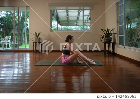 Woman exercising yoga on mat in indoor studio Woman exercising yoga on mat in indoor studio 142465063