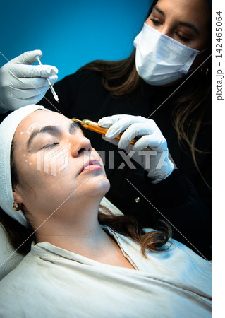 Doctor holding syringe and tool near patient's forehead 142465064