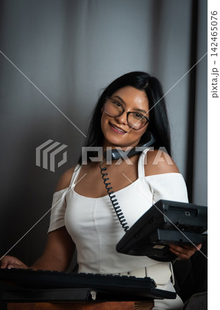 Smiling woman providing customer service assistance on telephone Smiling woman providing customer service assistance on telephone 142465076