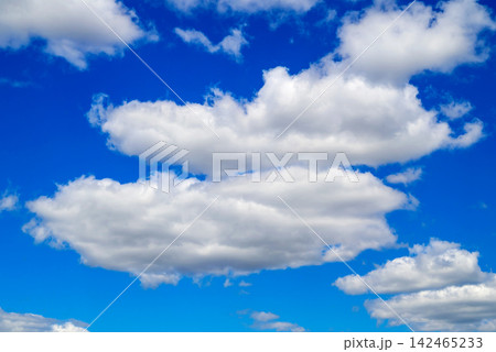 two large white clouds positioned one above the other in a vibrant blue sky two large white clouds positioned one above the other in a vibrant blue sky 142465233